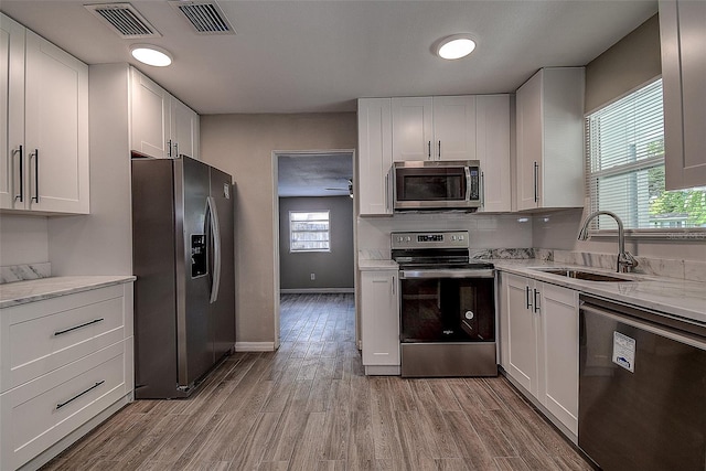 kitchen with stainless steel appliances, a wealth of natural light, and white cabinets