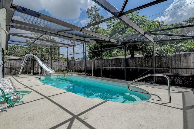 view of pool with a water slide, a patio, and glass enclosure