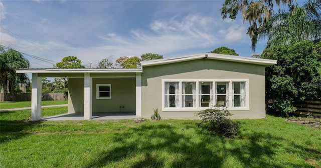 back of property featuring a lawn, a patio area, fence, and stucco siding