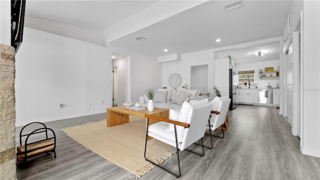 living room featuring baseboards, light wood finished floors, visible vents, and recessed lighting