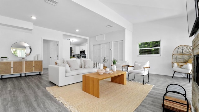 living area with recessed lighting, wood finished floors, visible vents, and baseboards