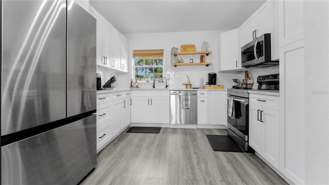 kitchen featuring tasteful backsplash, light wood-style flooring, stainless steel appliances, light countertops, and white cabinetry