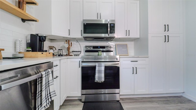 kitchen featuring stainless steel appliances, light countertops, light wood-style flooring, and white cabinetry