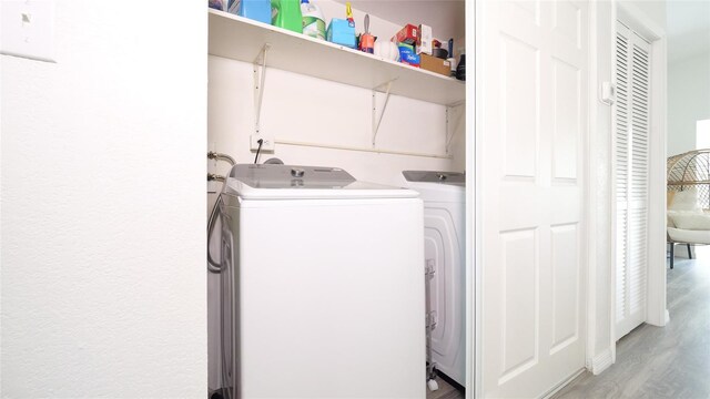 laundry room with laundry area, light wood finished floors, and washer and clothes dryer