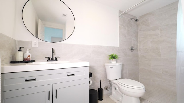 bathroom featuring toilet, visible vents, vanity, tile walls, and tiled shower