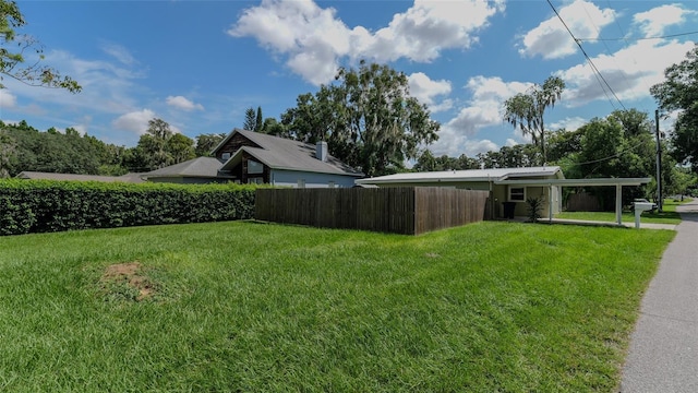 view of yard featuring fence and a carport