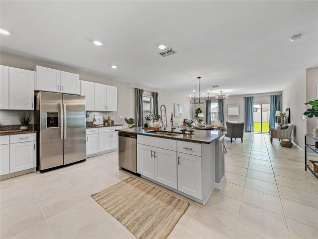 kitchen with sink, an island with sink, a notable chandelier, white cabinetry, and appliances with stainless steel finishes