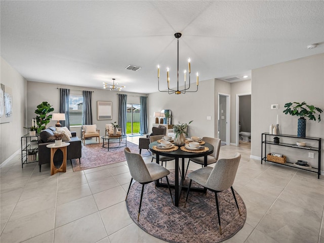 dining space featuring light tile patterned flooring, a notable chandelier, and a textured ceiling