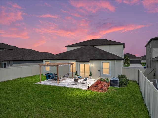 back house at dusk featuring a lawn, central air condition unit, and a patio area