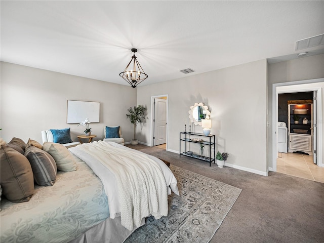 bedroom featuring light carpet, a chandelier, and washer / dryer