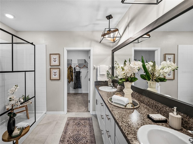 full bath featuring tile patterned floors, a sink, a walk in closet, and a stall shower