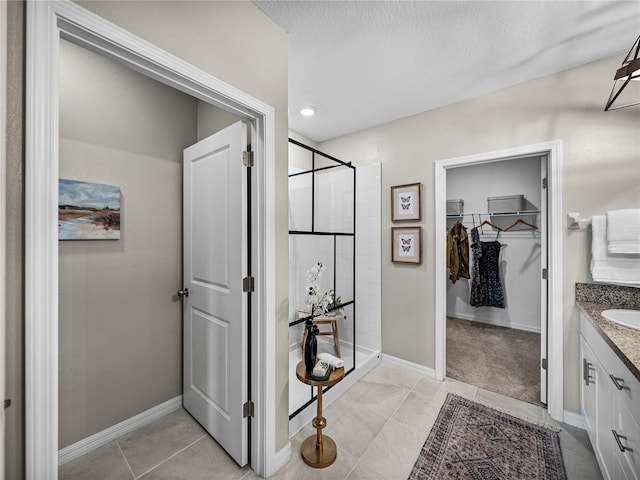 bathroom with tile patterned floors, a textured ceiling, a shower with door, and vanity