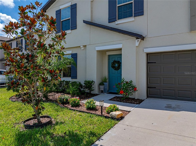 doorway to property with a garage and a lawn