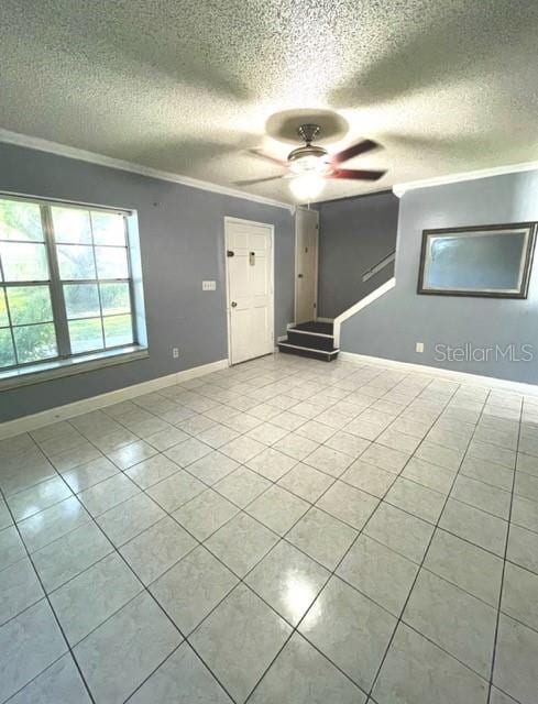 tiled empty room featuring ceiling fan, a textured ceiling, and ornamental molding