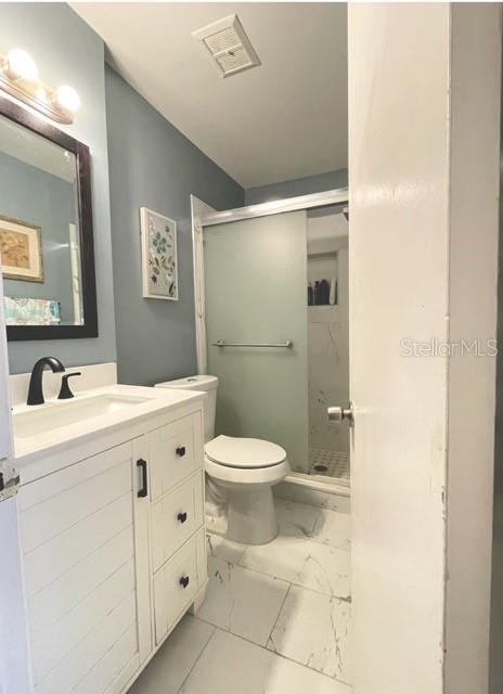 bathroom featuring tile patterned flooring, toilet, vanity, and a shower with shower door