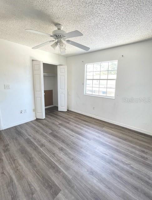 unfurnished bedroom featuring a textured ceiling, a closet, ceiling fan, and dark hardwood / wood-style flooring