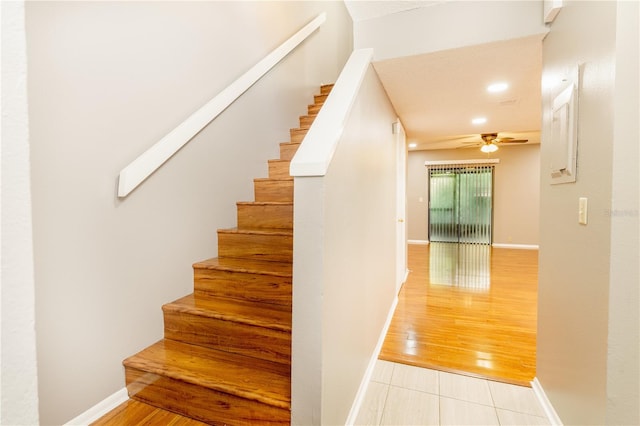 stairs featuring ceiling fan and wood-type flooring