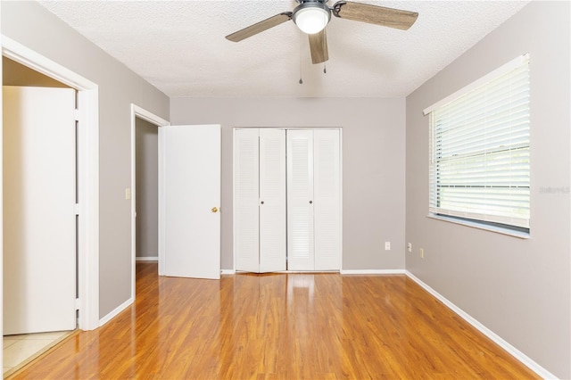 unfurnished bedroom with a closet, a textured ceiling, ceiling fan, and light hardwood / wood-style floors