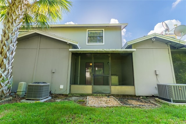 rear view of property featuring central AC unit and a lawn