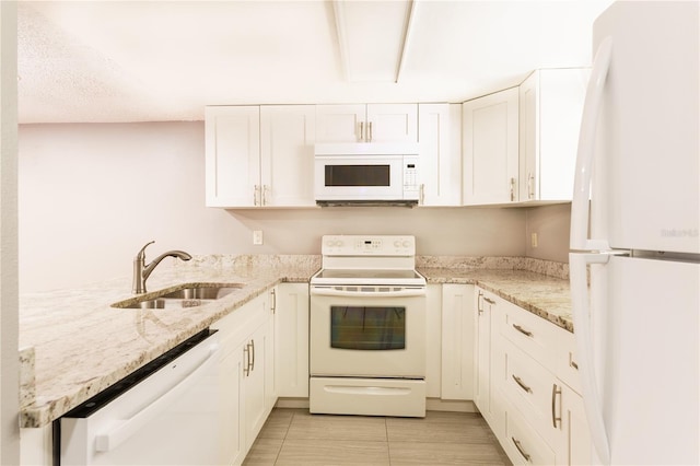 kitchen featuring white cabinetry, white appliances, light stone counters, and sink