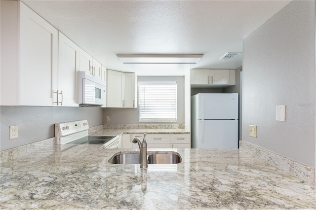 kitchen featuring white appliances, light stone countertops, white cabinetry, sink, and a textured ceiling