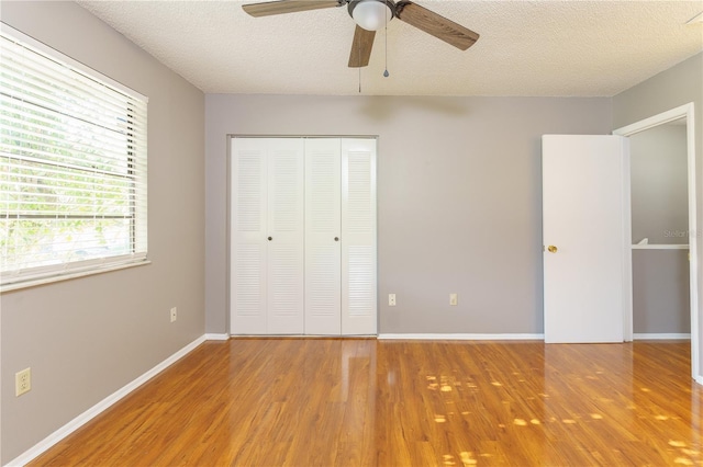 unfurnished bedroom with a textured ceiling, hardwood / wood-style flooring, ceiling fan, and a closet