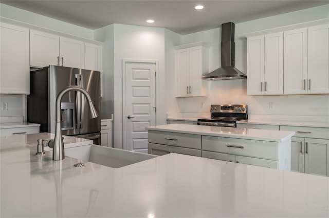 kitchen with wall chimney range hood, appliances with stainless steel finishes, a sink, light countertops, and recessed lighting