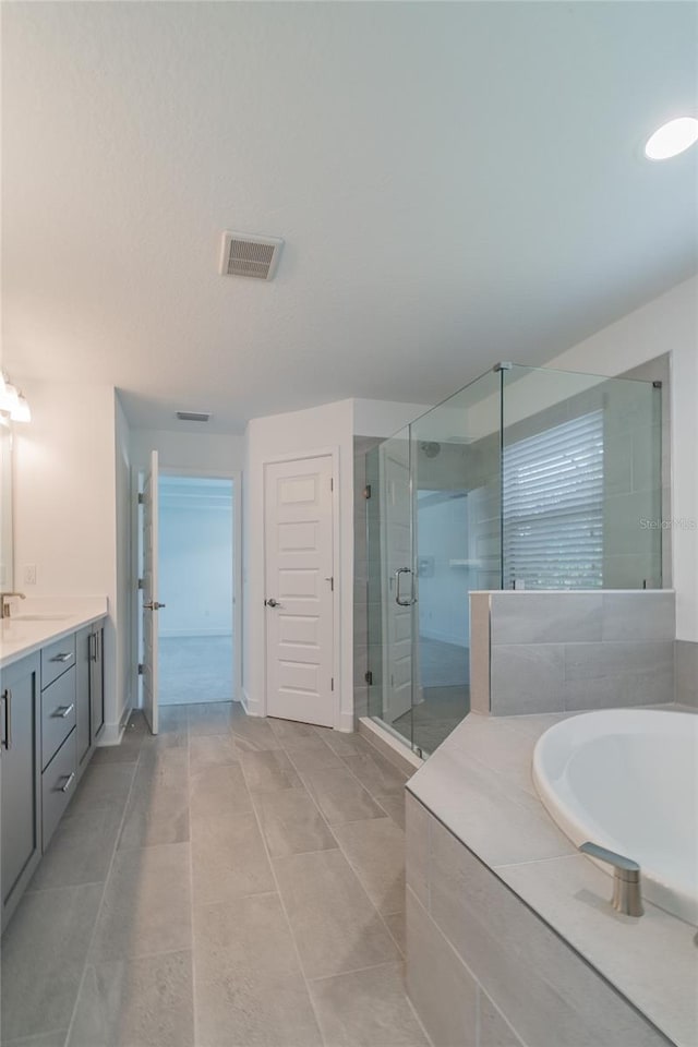 bathroom featuring vanity, a stall shower, a bath, and visible vents
