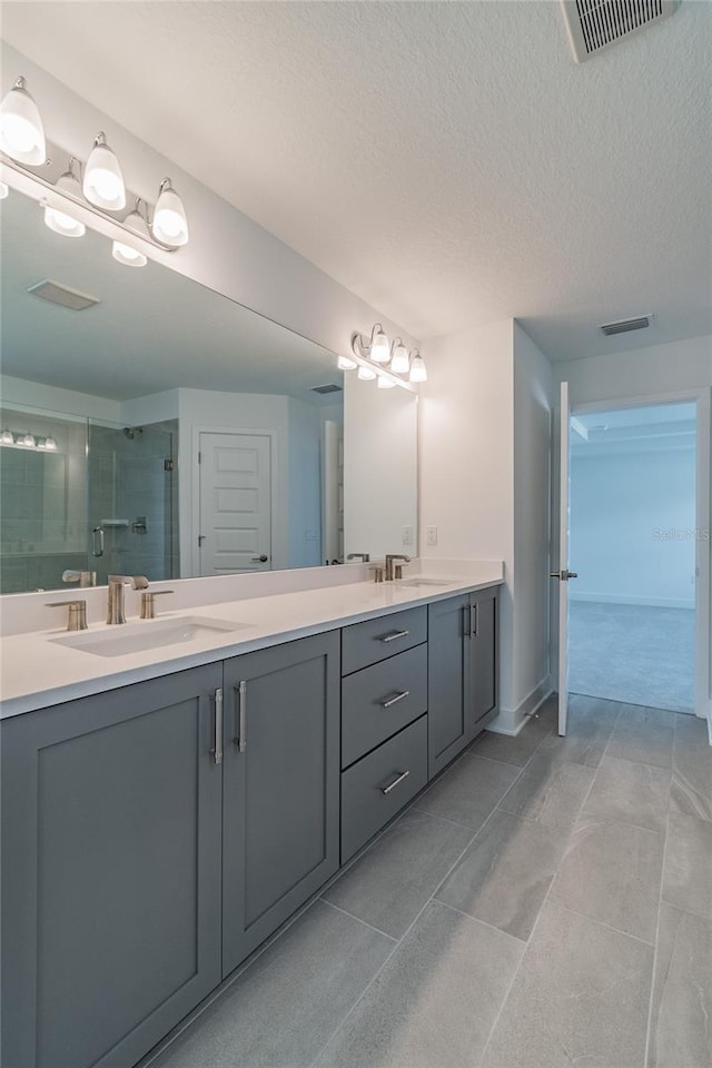 bathroom featuring tile patterned floors, a textured ceiling, a shower with door, and vanity