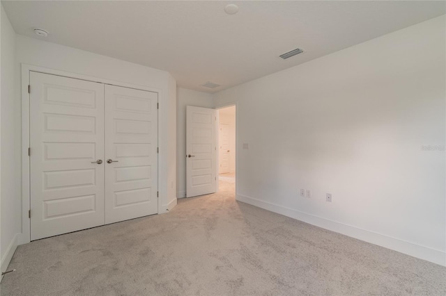 unfurnished bedroom featuring a closet and light carpet