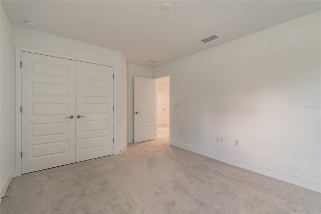 unfurnished bedroom with carpet floors, baseboards, visible vents, and a closet