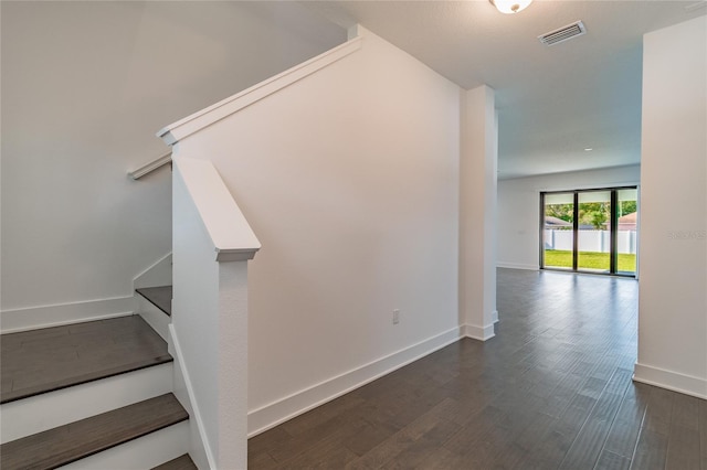stairway featuring baseboards, wood finished floors, and visible vents