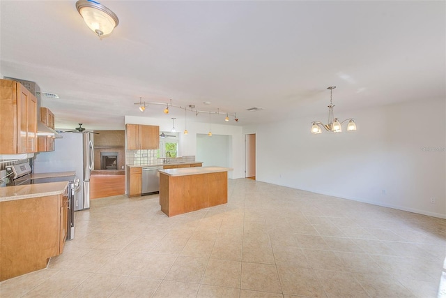 kitchen featuring a center island, stainless steel appliances, hanging light fixtures, a chandelier, and decorative backsplash