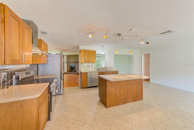 kitchen featuring sink, pendant lighting, decorative backsplash, a kitchen island, and appliances with stainless steel finishes