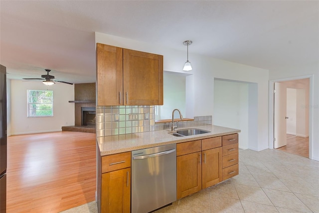 kitchen with dishwasher, backsplash, sink, decorative light fixtures, and light hardwood / wood-style floors