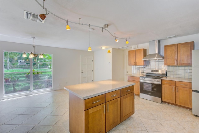 kitchen with pendant lighting, wall chimney range hood, stainless steel range, tasteful backsplash, and a kitchen island