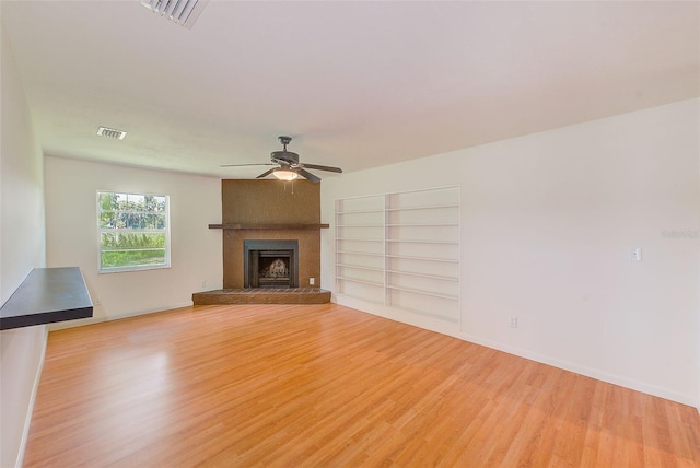 unfurnished living room featuring a fireplace, light wood-type flooring, and ceiling fan