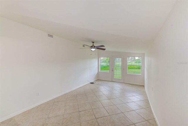 empty room with light tile patterned floors, vaulted ceiling, and ceiling fan