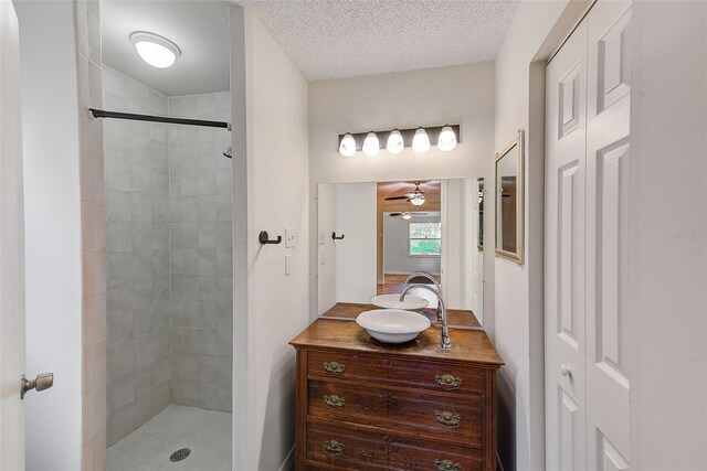 bathroom with vanity, ceiling fan, and a tile shower