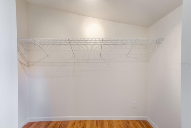 walk in closet with lofted ceiling and hardwood / wood-style flooring