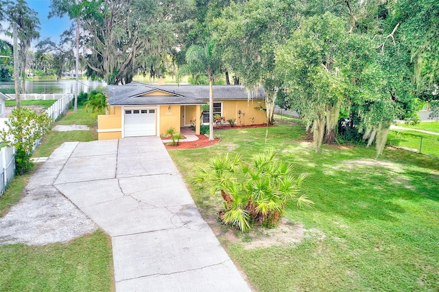 ranch-style house featuring a garage, a water view, and a front lawn