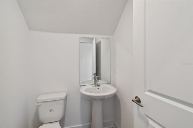 bathroom with vaulted ceiling, toilet, and a textured ceiling