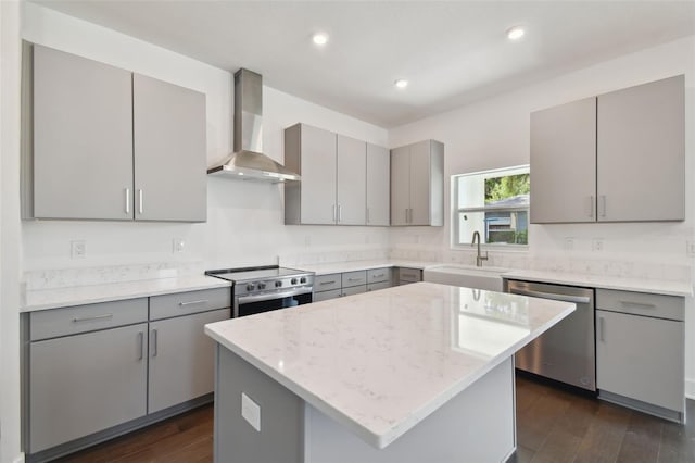 kitchen featuring sink, dark wood-type flooring, light stone counters, stainless steel appliances, and wall chimney range hood