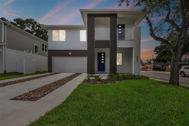 contemporary house with a balcony, a yard, and a garage