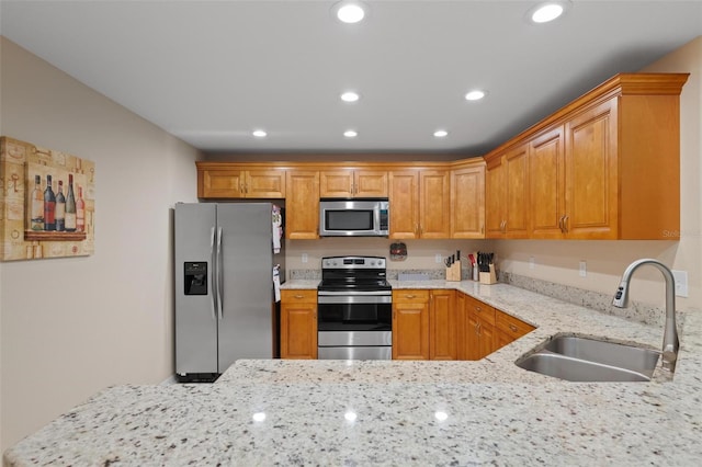 kitchen featuring appliances with stainless steel finishes, sink, and light stone countertops