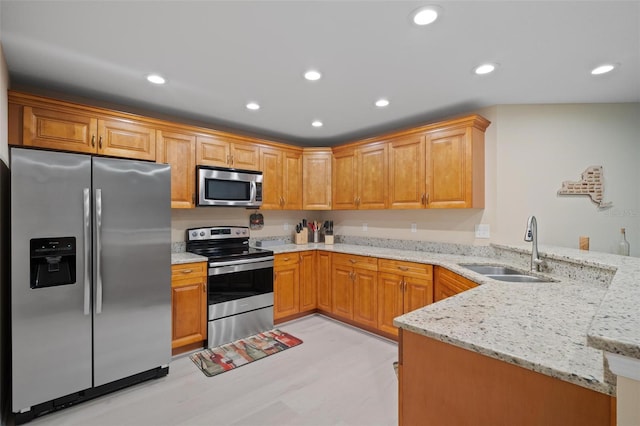 kitchen featuring appliances with stainless steel finishes, sink, kitchen peninsula, and light stone countertops