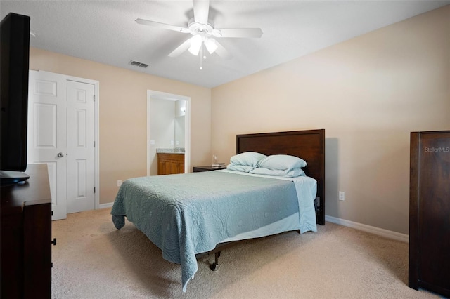 bedroom with ceiling fan, light carpet, and connected bathroom