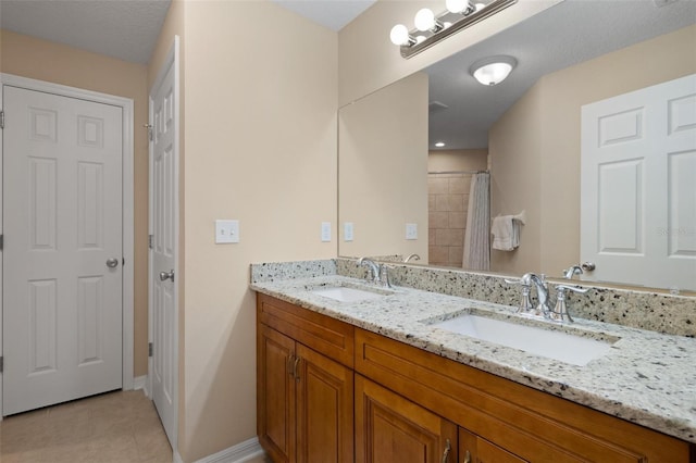 bathroom with tile patterned floors, a textured ceiling, and dual bowl vanity