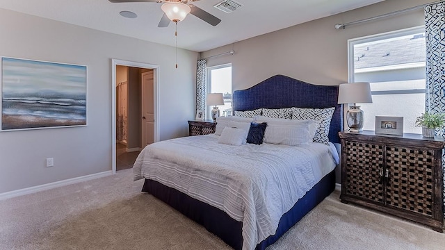 carpeted bedroom with ceiling fan, multiple windows, and ensuite bathroom