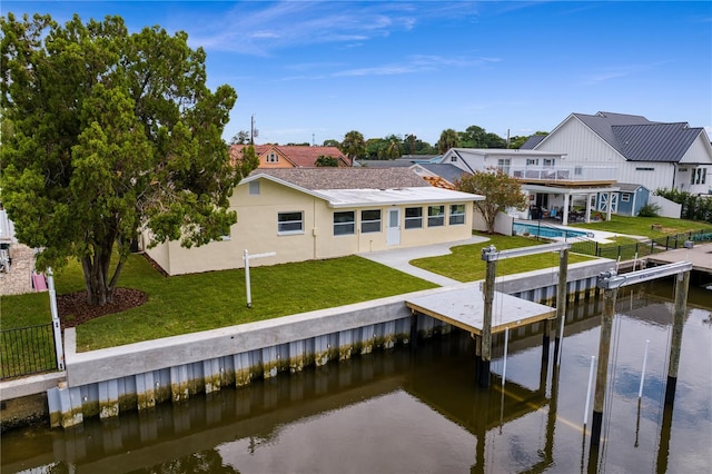 view of dock with a lawn, a patio area, a water view, and a balcony